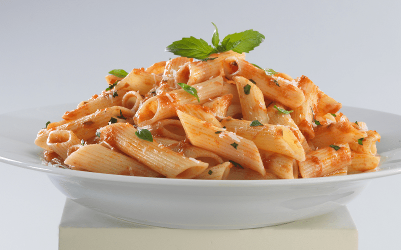 pasta on white plate with basil leaf on top