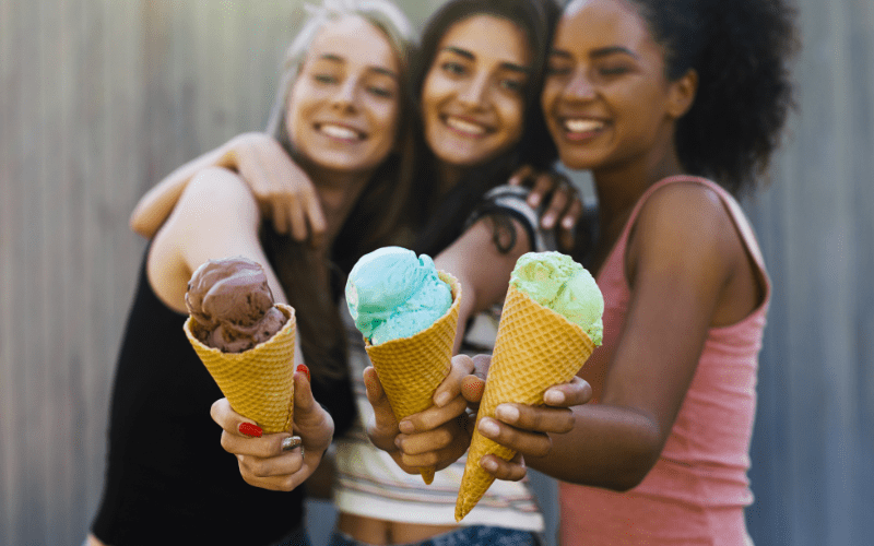 three young women holding ice cream cones and smiling