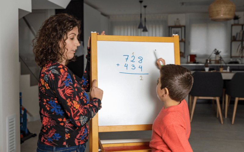 A mother teaching her son math using a whiteboard