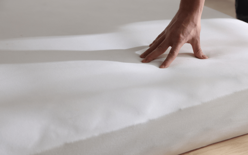 a hand on a mattress that is encased for dust mite allergies
