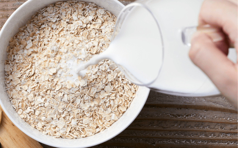 Oatmeal in a bowl with milk being poured to create homemade oatmeal shakes.